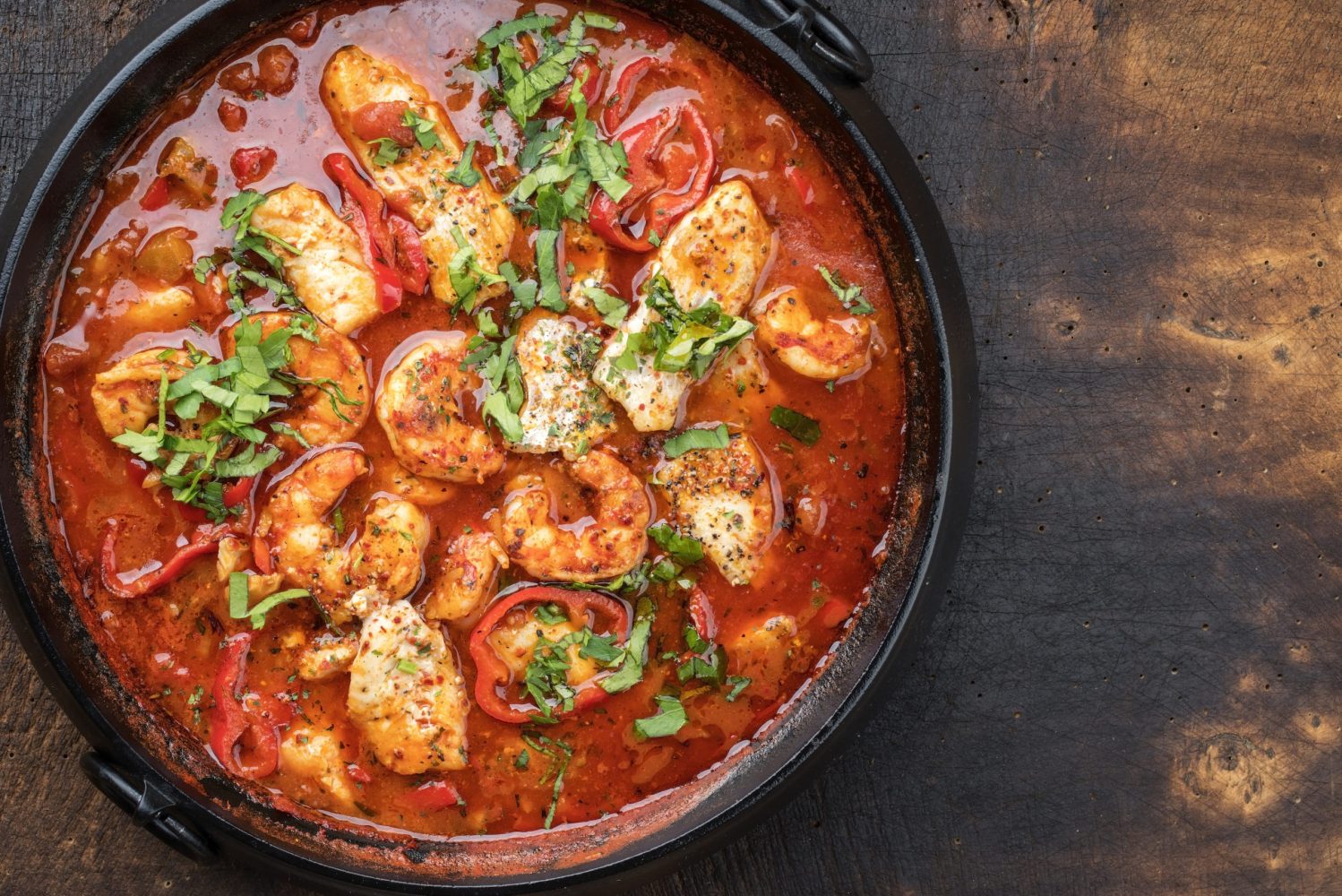 Traditional Creole cajun court bouillon with fish and seafood gumbo chowder stew as top view in a pot with copy space right