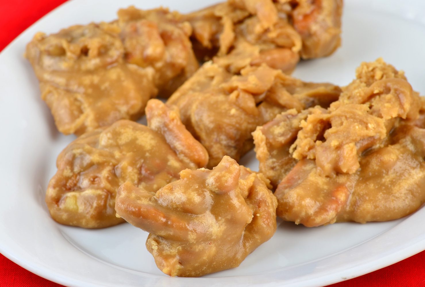 Closeup of platter of pecan pralines in selective focus against red background